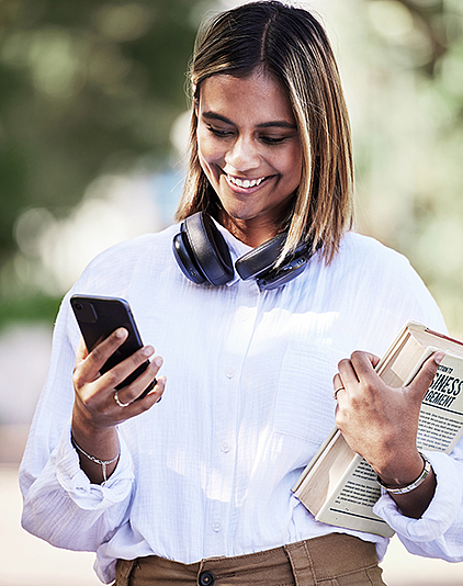 Frau mit Buch im Arm und Handy in der Hand